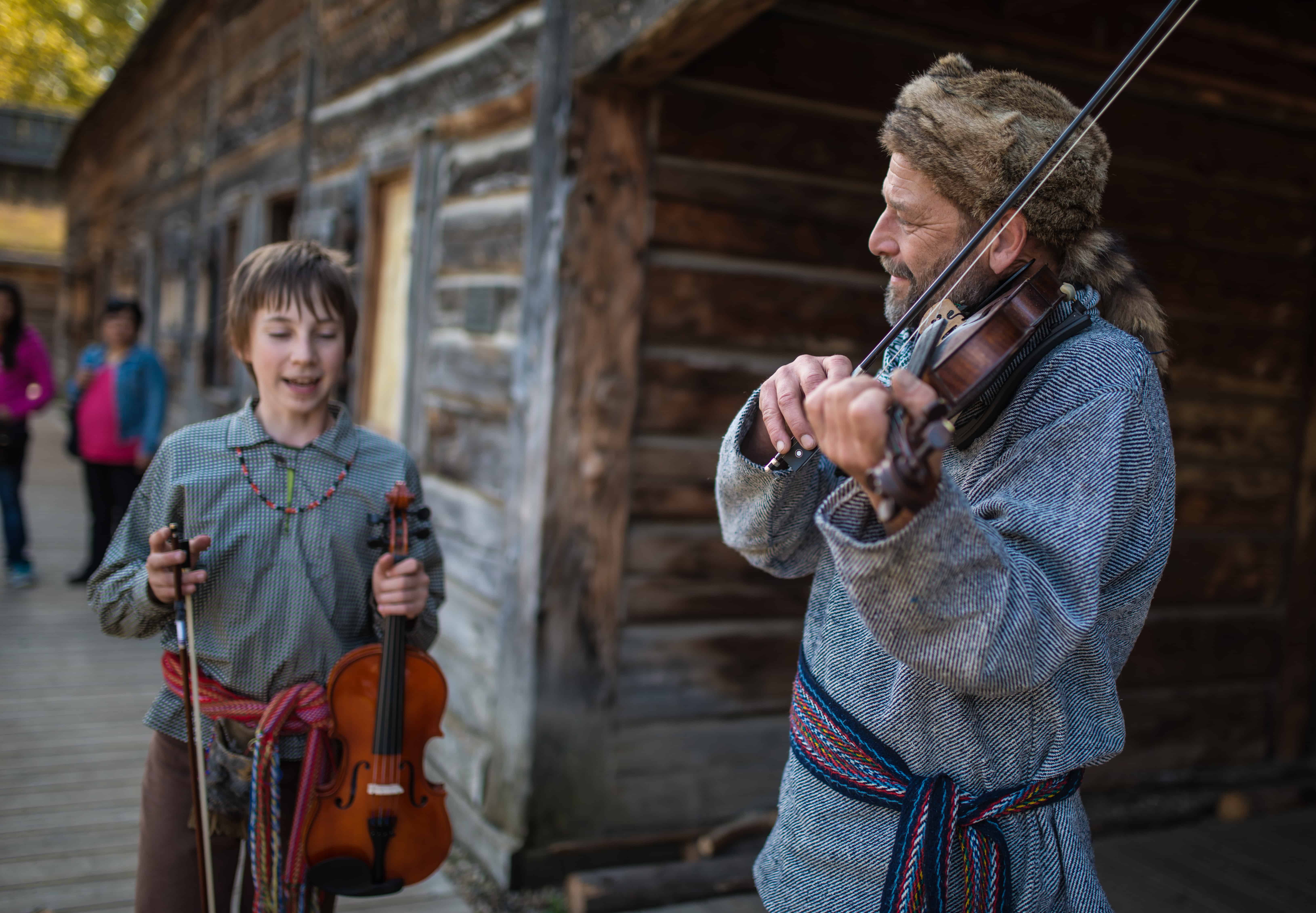 Zwei verkleidete Menschen spielen Geige und informieren über die kanadische Geschichte