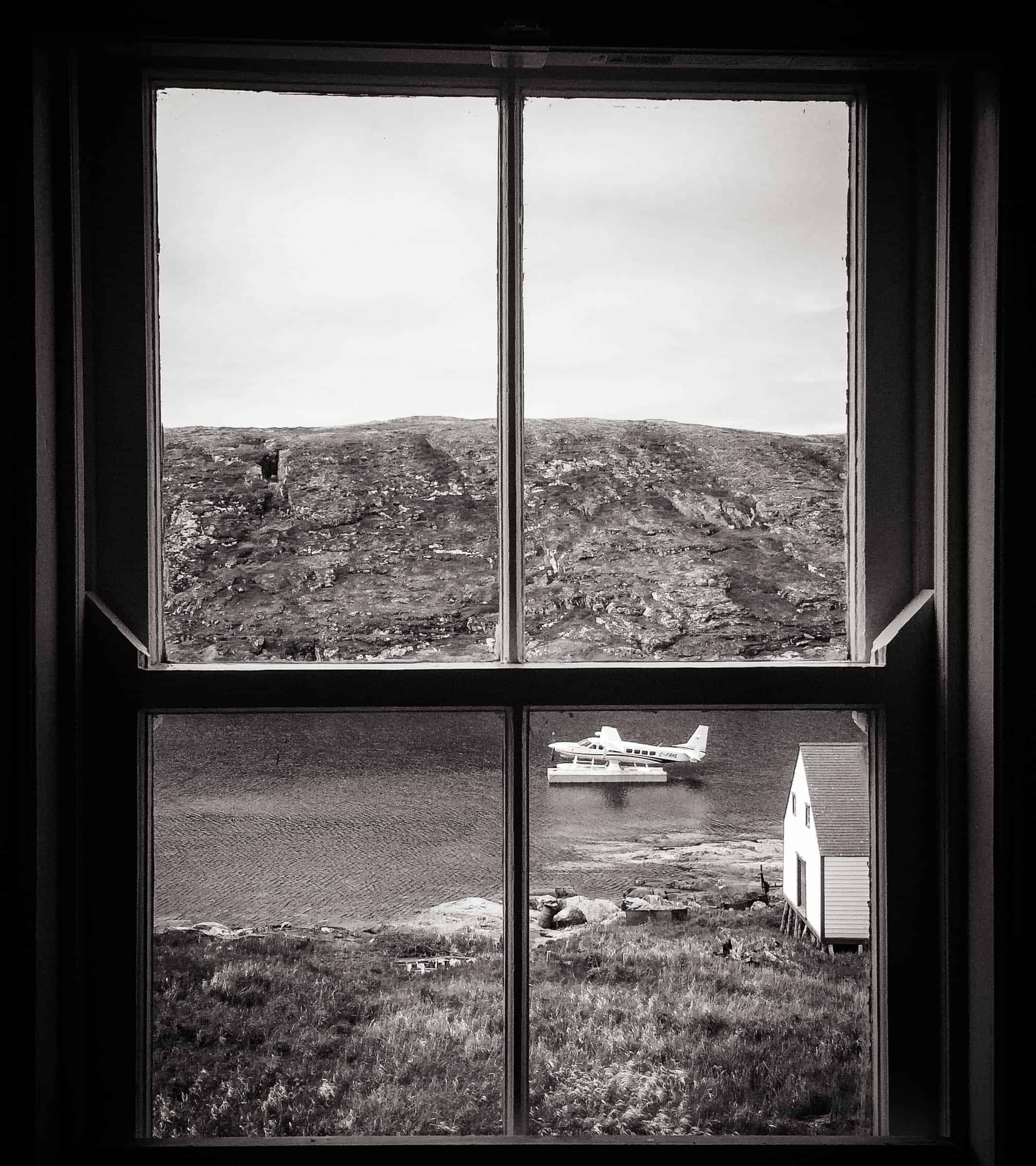 Schwarz-weiß-Foto aus einem Fenster auf ein Wasserflugzeug in Kanada