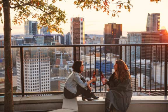 Zwei Frauen sitzen vor der Kulisse Vancouvers und trinken Wein