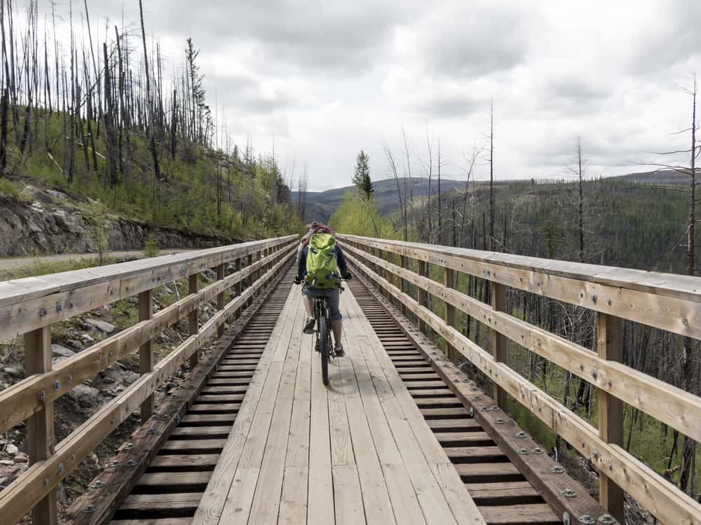Ein Backpacker fährt mit dem Fahrrad über eine Brücke auf dem Trans Canada Trail
