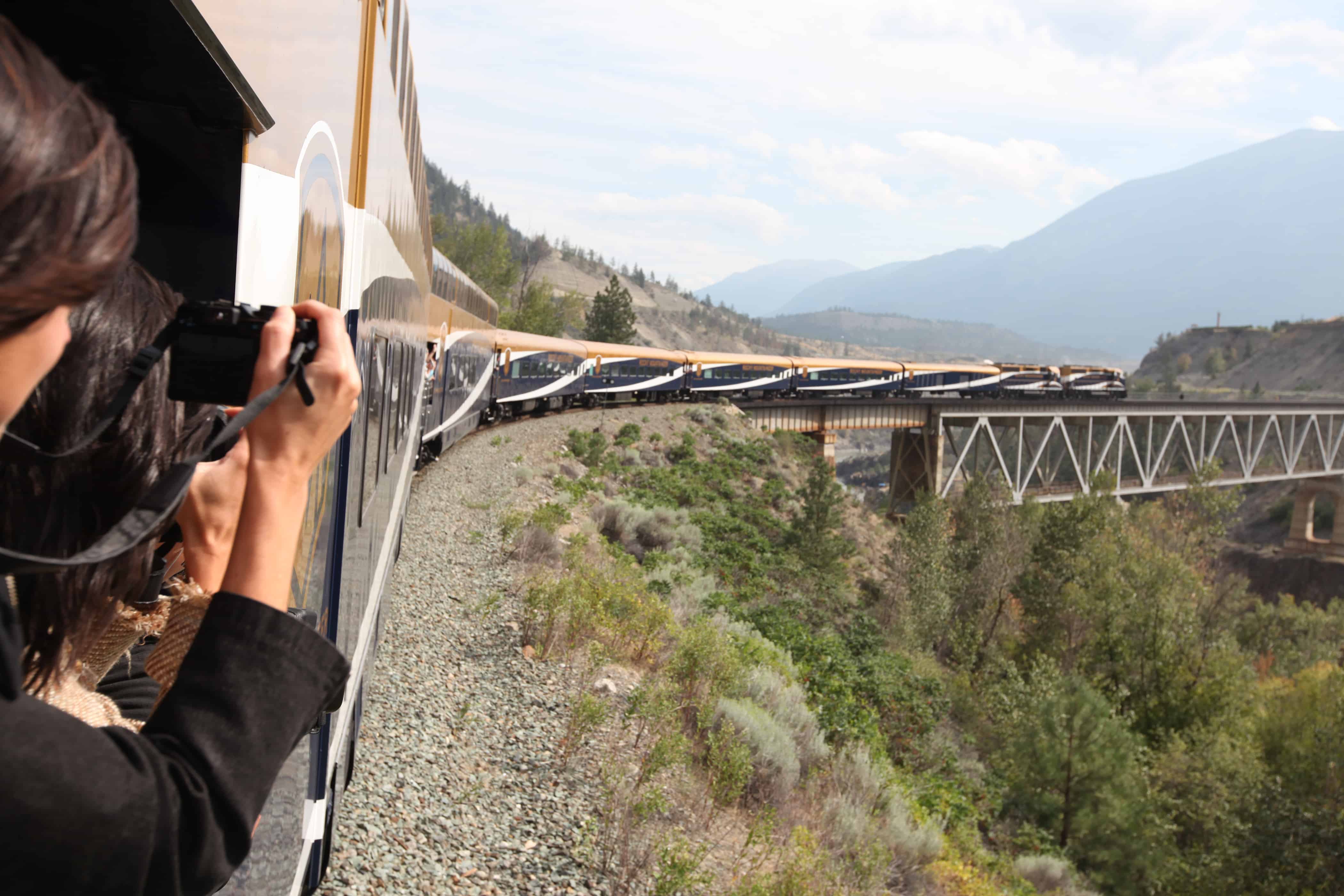 Zuggäste fotografieren aus Fenster während Zug eine Brücke in Kanada passiert