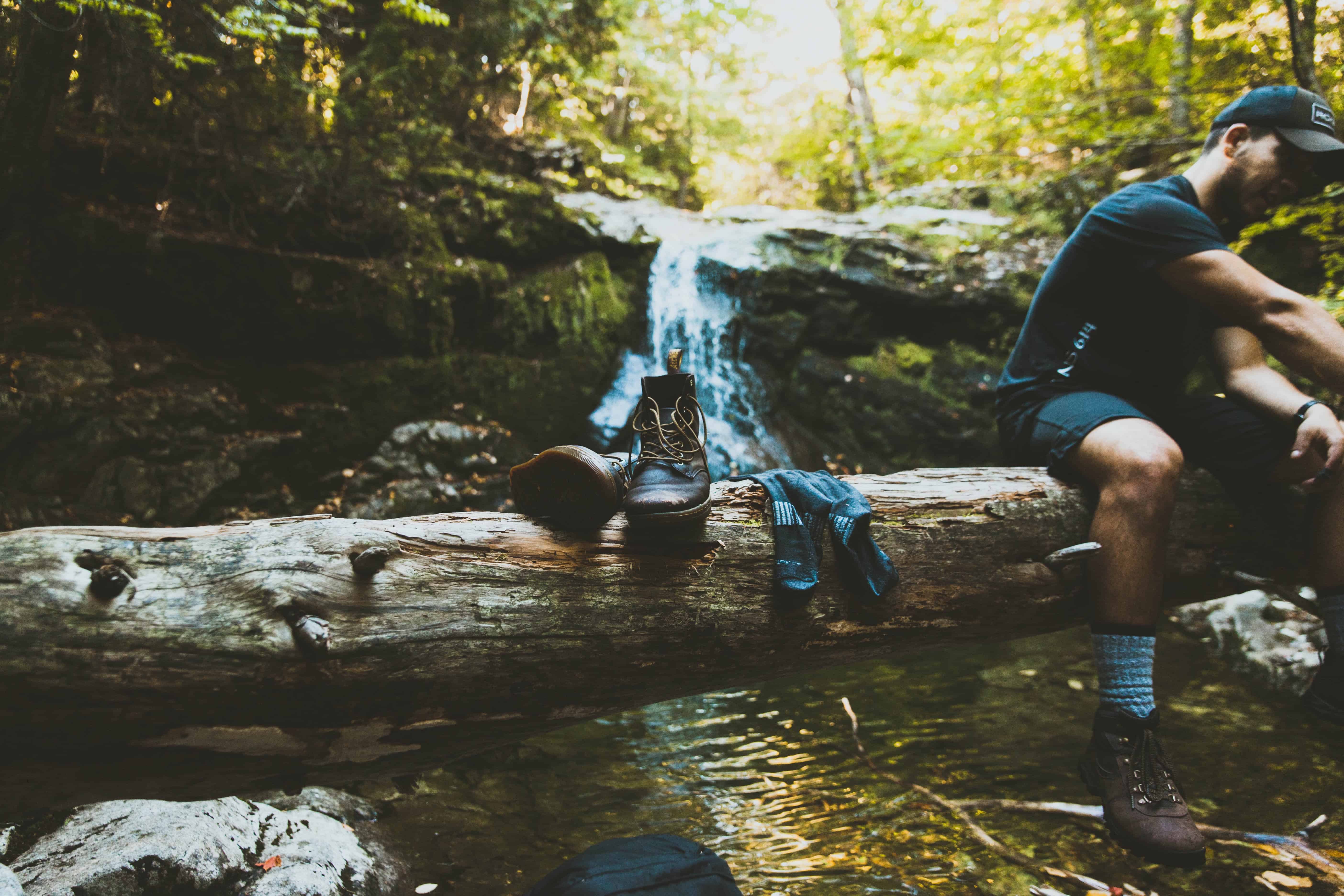 Wanderer wäscht sich Füße im Fluss nach einer Wanderung