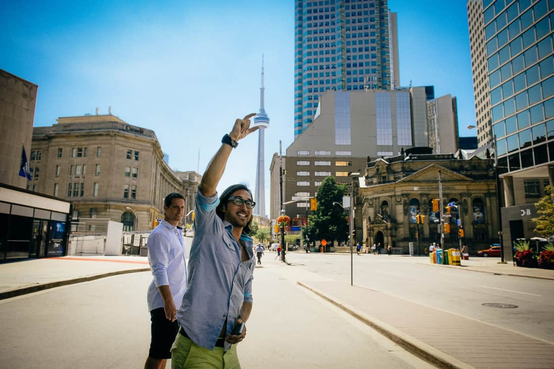 Mann nimmt Foto vor dem CN Tower in Toronto auf