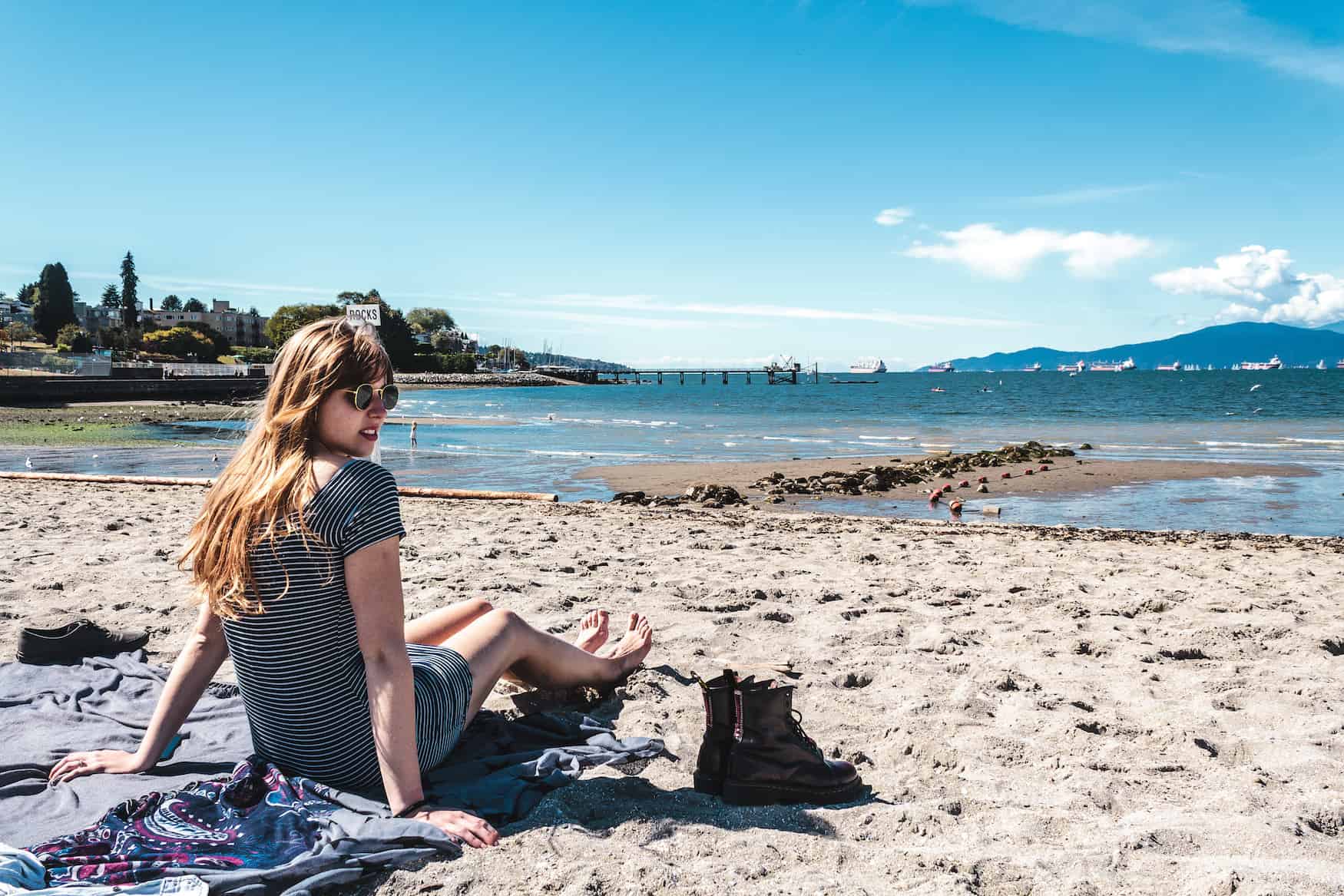 Mädchen sitzt am Kitsilano Beach und guckt in die Kamera