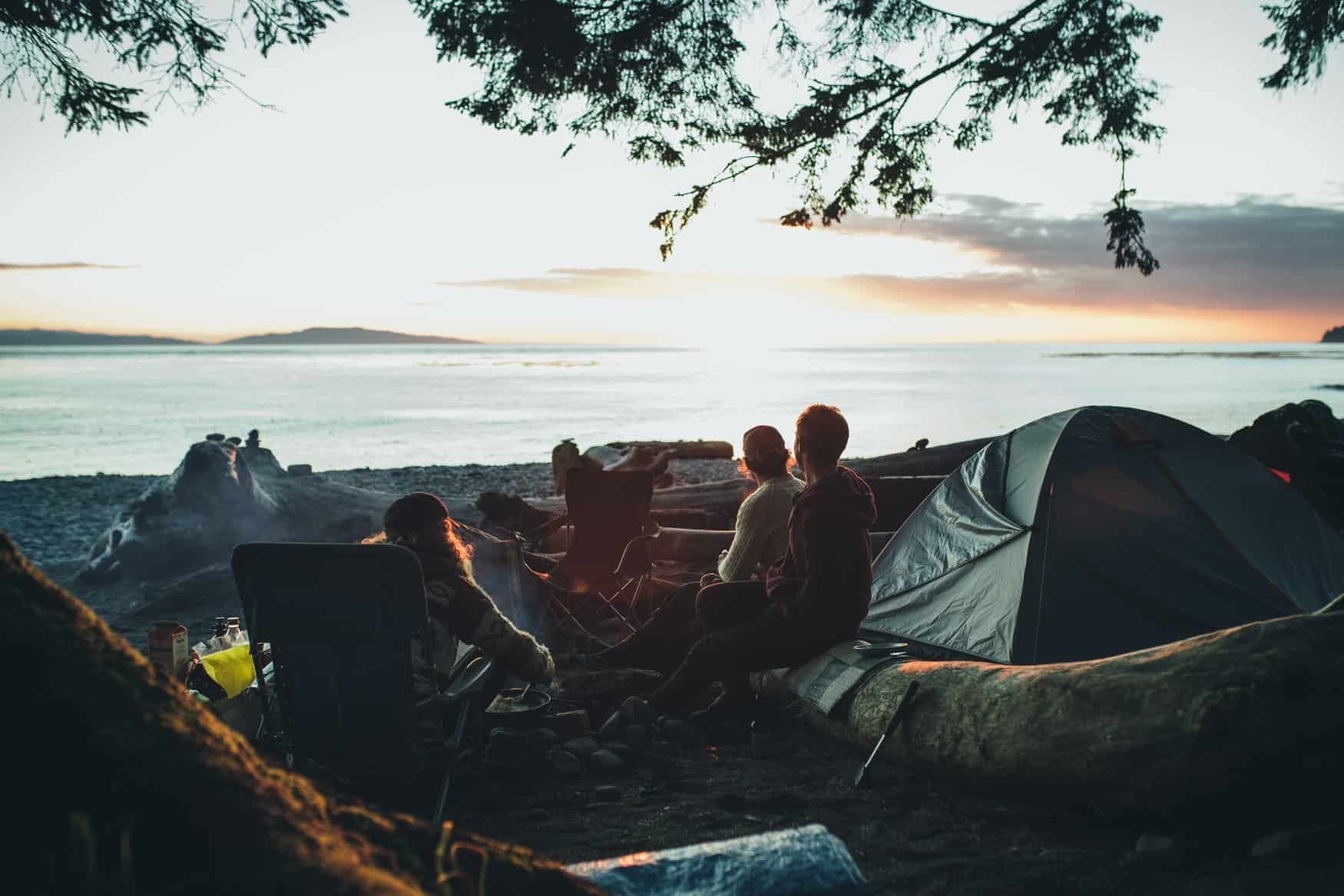 Freundesgruppe sitzt um Lagerfeuer beim Camping in Kanada
