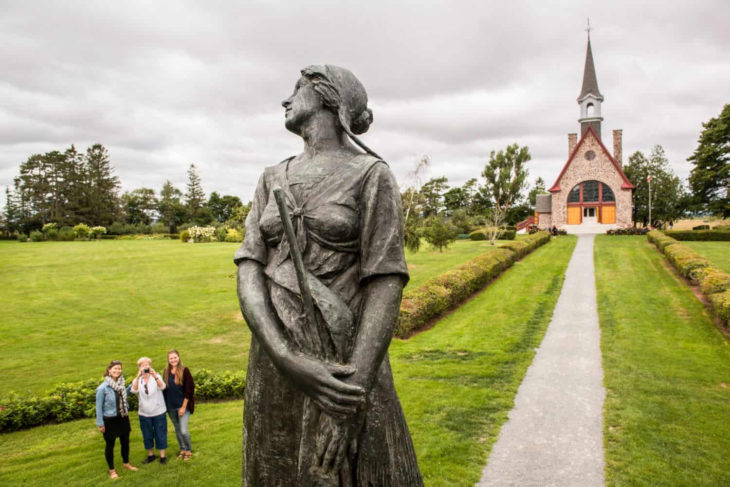 Besucher bestaunen die Evangeline Statue in den Victorian Gardens, mit der Memorial Church im Hintergrund.