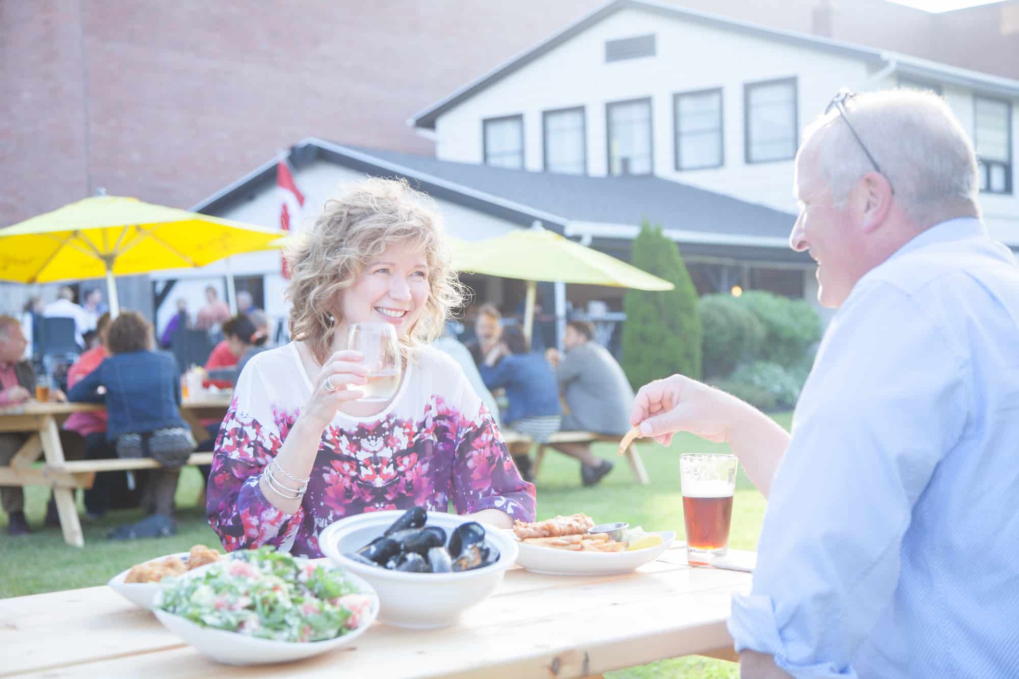 Zwei Menschen sitzen auf Outdoor Terrasse eines Street Food Festes auf prince Edward Island und genießen die Kulinarik