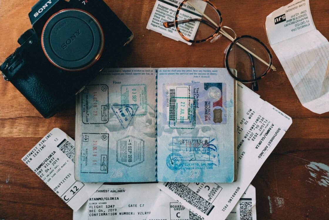 Reisepass mit Stempeln, Kamera, Brille und andere Reisedokumente liegen auf einem Tisch