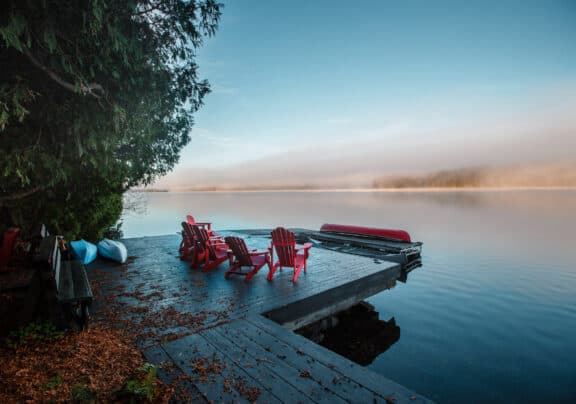 Rote Muskoka-Stühle an Seeufer