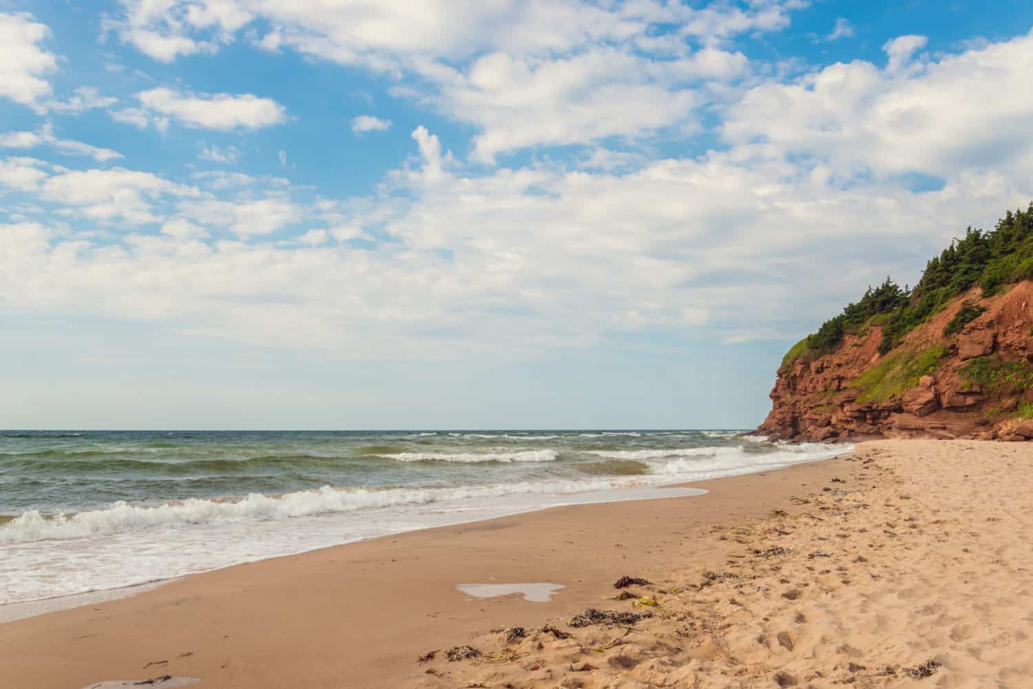 Singing Sands, Basin Head Provincial Park, P.E.I. Prince Edward Island), Kanada. Der singende Strand am Wasser mit Felsen im Hintergrund.