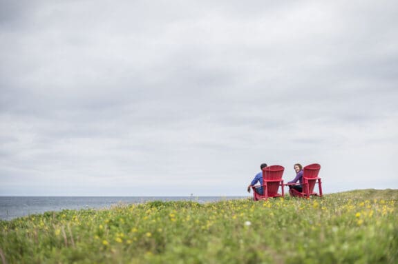 Pärchen sitzt auf roten Stühlen in der Landschaft von Neufundland