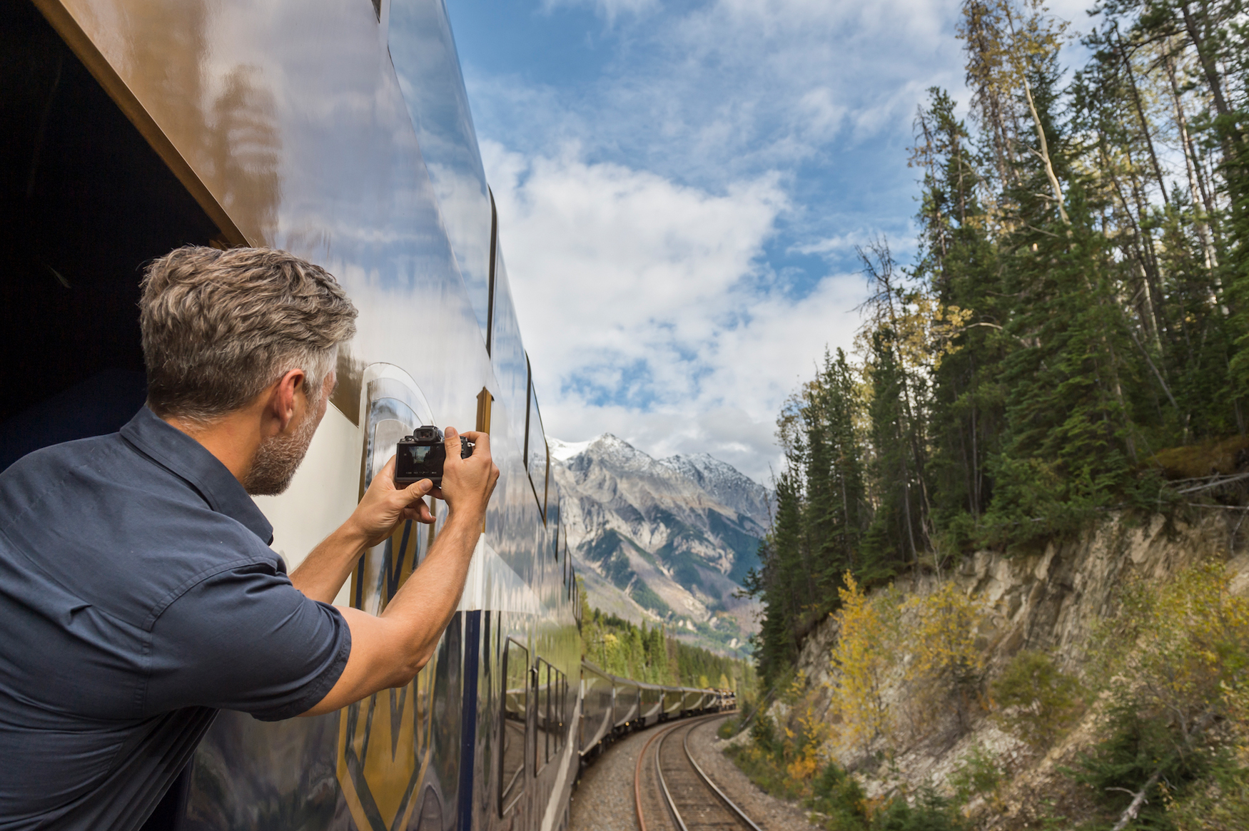 Mann schießt Fotos während einer Fahrt mit dem Zug durch Kanada