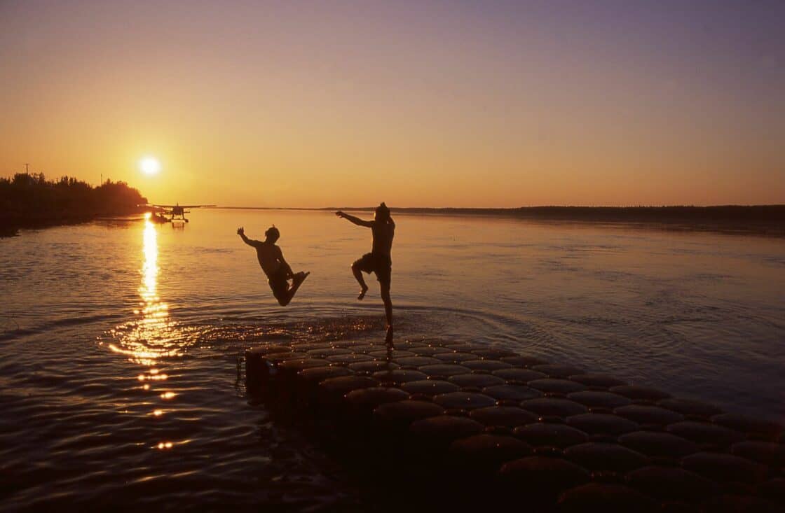 Menschen springen in See während der Mitternachtssonne in den Northwest Territories