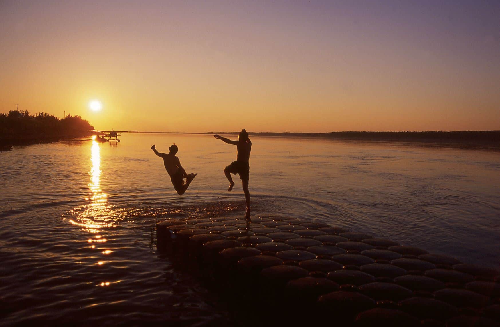 Menschen springen in See während der Mitternachtssonne in den Northwest Territories