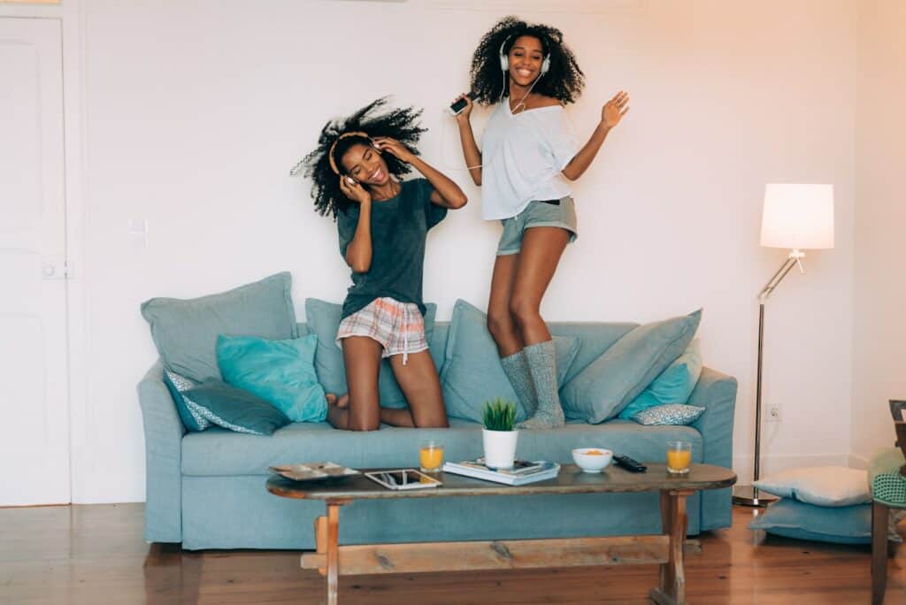 Frauen tanzen auf einem Sofa zur Playlist von Spotify