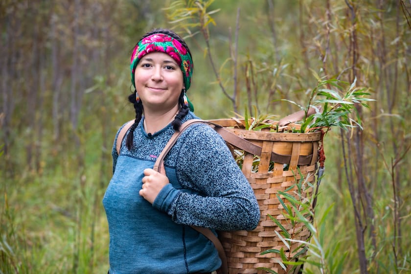 Michela Carrière der Cree trägt einen geflochtenen Korb auf dem Rücken in Sasketchewan