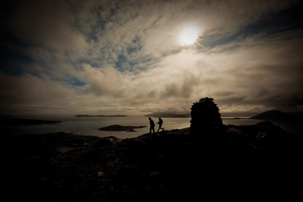 Zwei Menschen spazieren in der Dunkelheit in Neufundland, während die Sonne sich hinter Wolken versteckt.