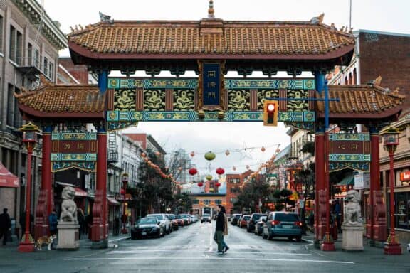 Zwei Personen laufen unter dem Gate of Harmonious Interest der Chinatown in Victoria