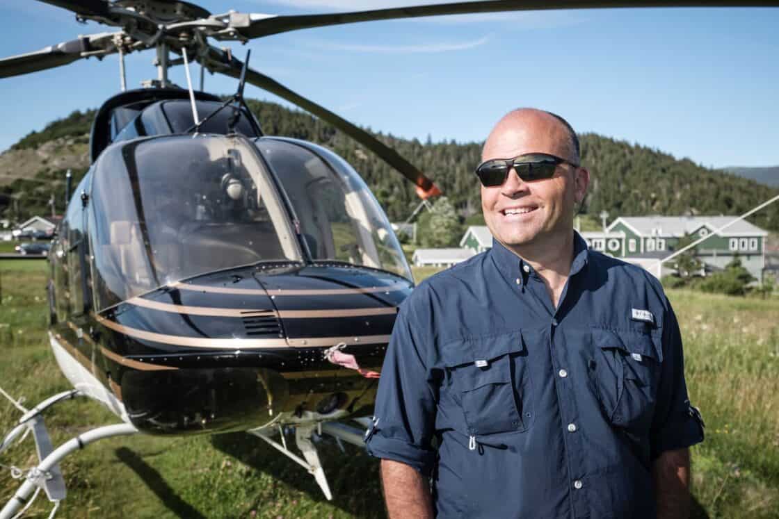 Stan Cook steht lächelnd vor seinem Helikopter