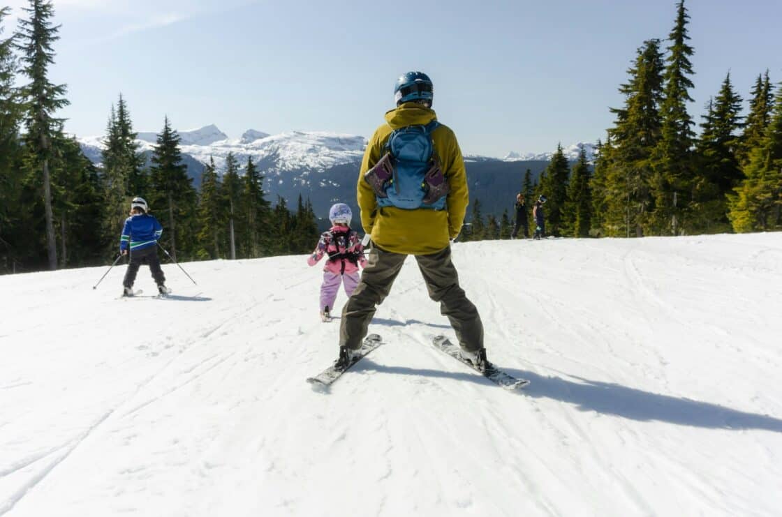 Ein Vater fährt Ski mit seinen Kindern auf der Skipiste