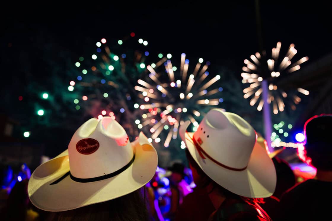 Zwei Personen tragen Cowboyhüte und schauen sich ein Feuerwerk an