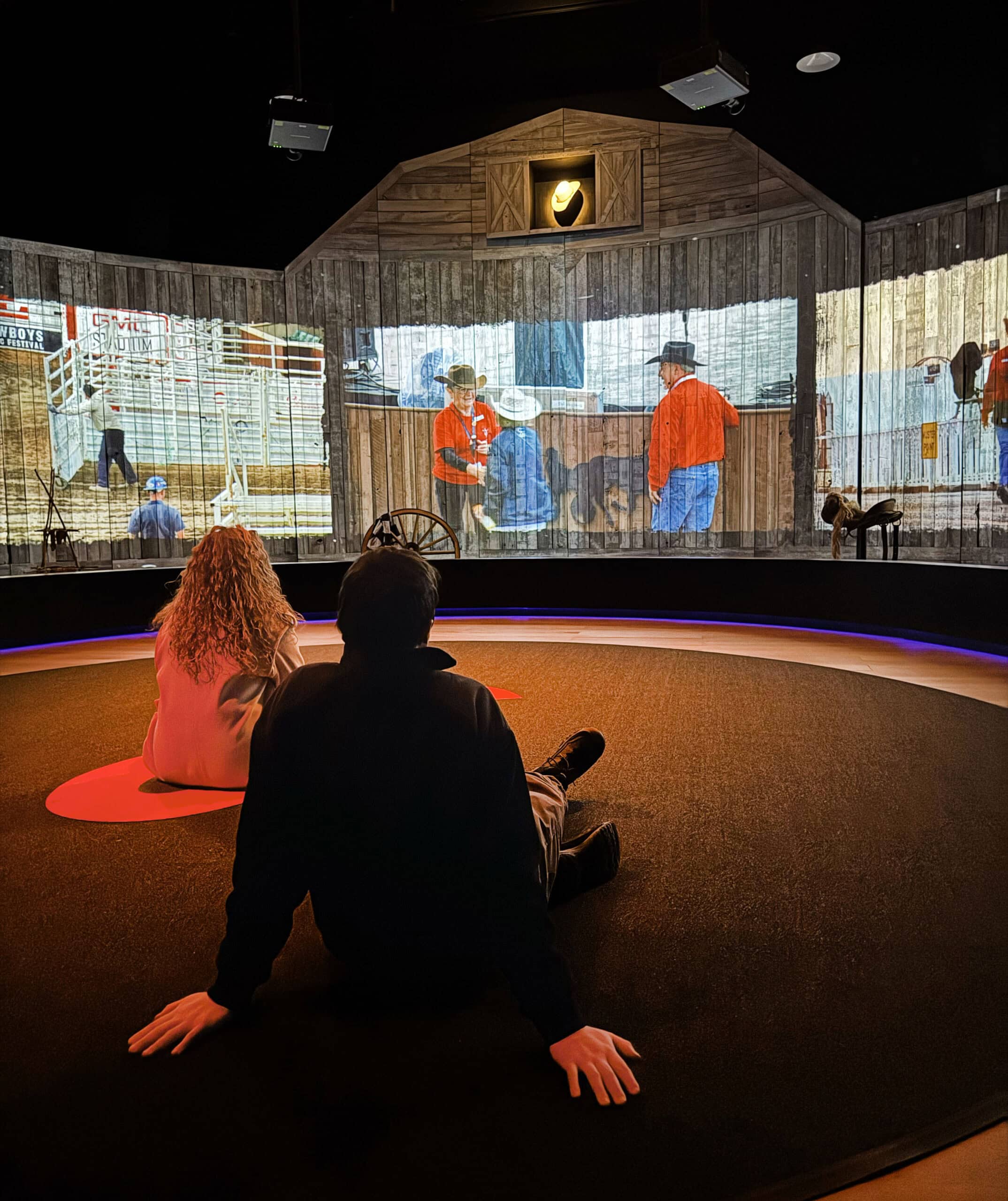 ZWei Menschen sitzen auf dem Boden und schauen sich die Multimedia-Show im Sam Centre in Calgary an zur Stampede