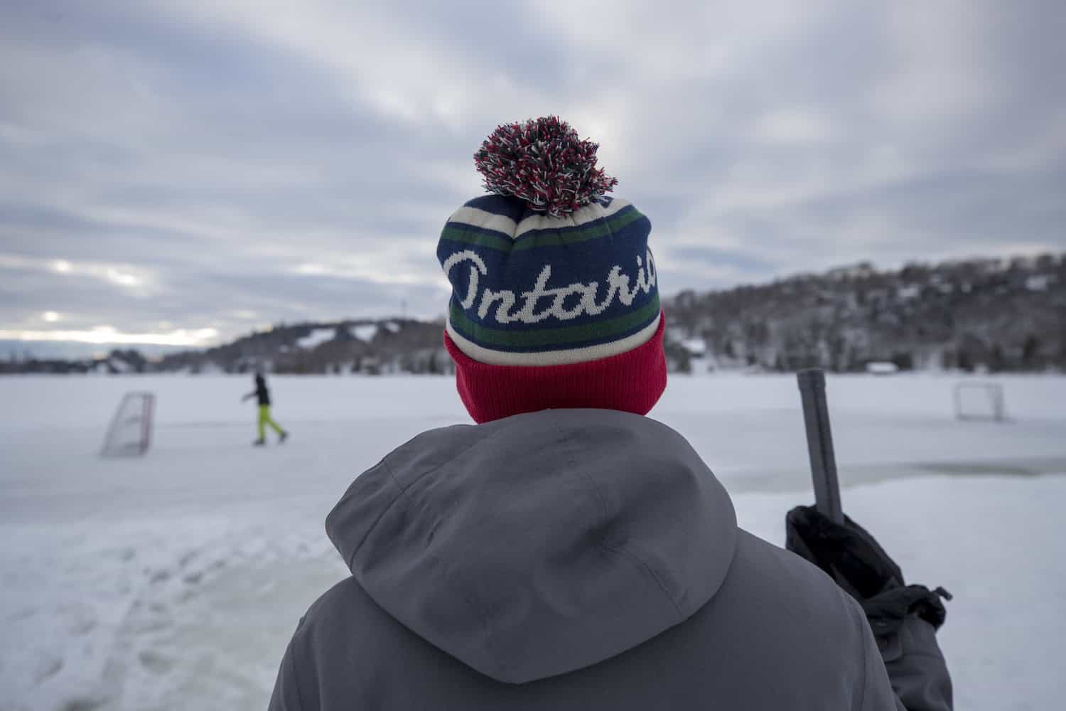 Person mit Ontario-Mütze und Hockeyschläger steht auf Eisfläche in Ontario.