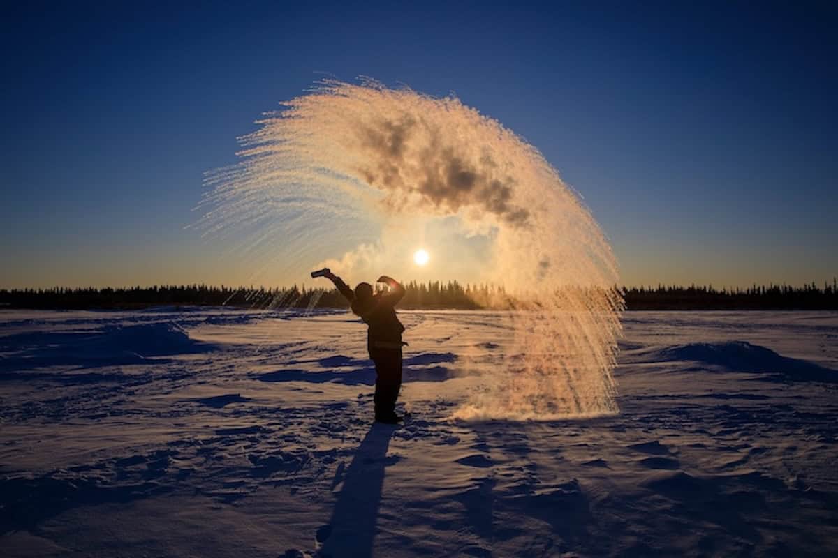 Person wirft Wasser in kalte Luft, das direkt zu Eis gefriert.