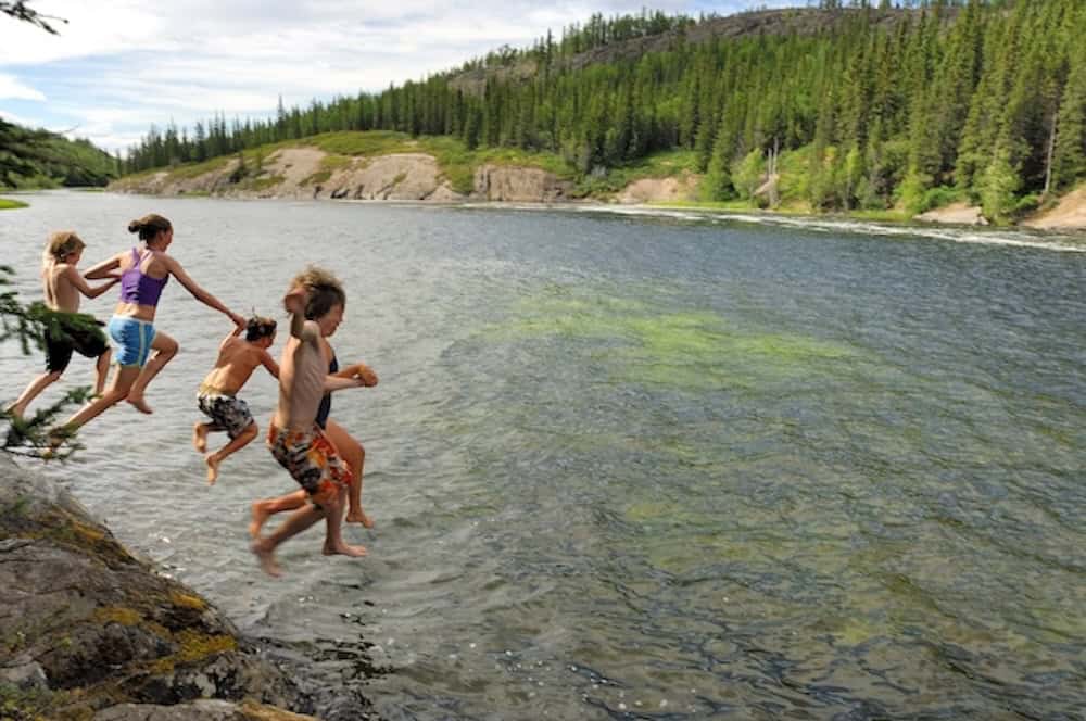 Kinder springen in den See an den Cameron Falls in den NWT.
