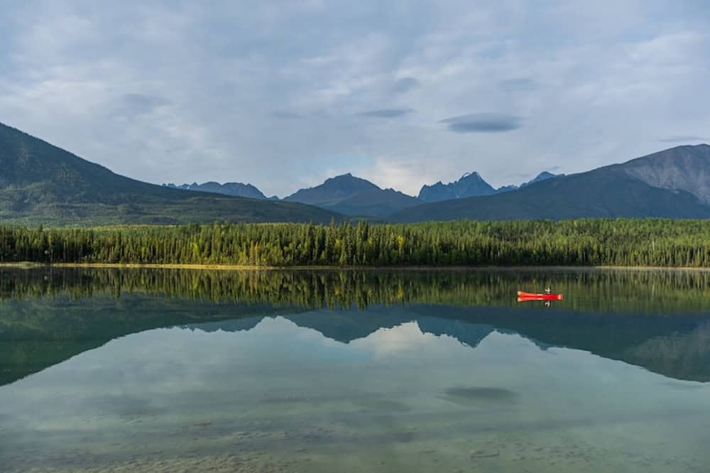 Ein Kanu fährt im Nahanni National Park in den NWT über einen See.
