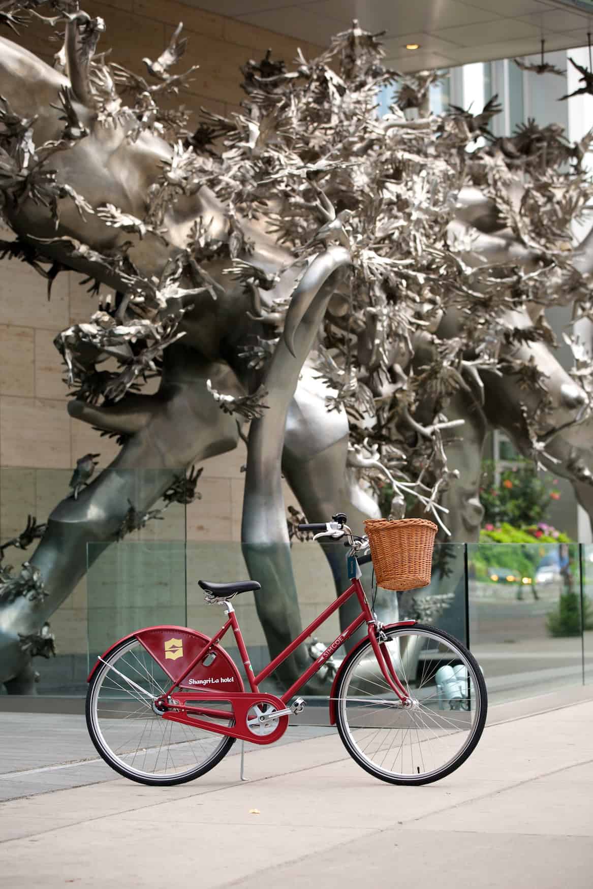 Ein rotes Fahrrad steht vor der Skulptur vor dem Shangri-La Toronto