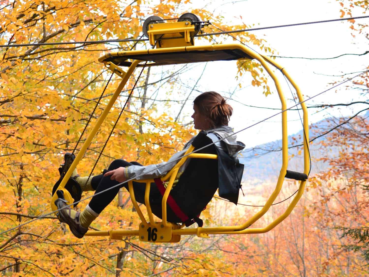 Frau im Vélo Volant in den Baumkronen im Naturresort Au Diable Vert in Sutto.